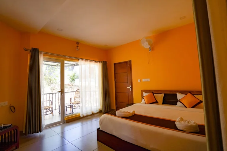 Bright and spacious luxury bedroom with private balcony access and modern amenities at the best resort in Wayanad.