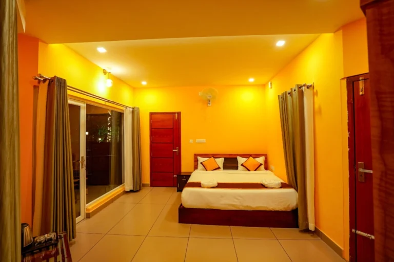 Spacious luxury bedroom with warm lighting, comfortable king-size bed, and modern interiors at the best resort in Wayanad.