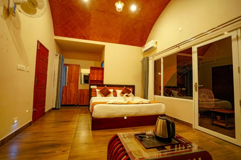 Elegant luxury bedroom with wooden flooring, large glass windows, and modern amenities at the best resort in Wayanad.
