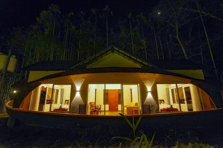Luxury dome-style forest cottage with panoramic glass windows and warm night lighting at the best resort in Wayanad.